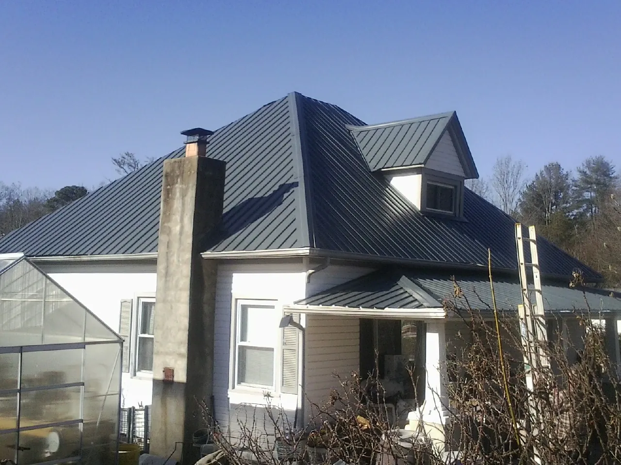 Dark blue standing seam metal roof on a white farmhouse with dormer — Slate & Tile Roof Repair by Roofing Brothers in Ransomville