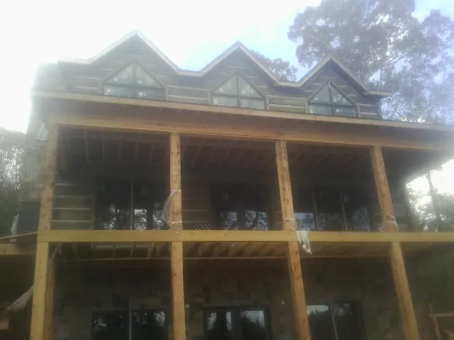 Dormers and porch framing on a large log home under construction — Roof Coating work by our crew in Ransomville