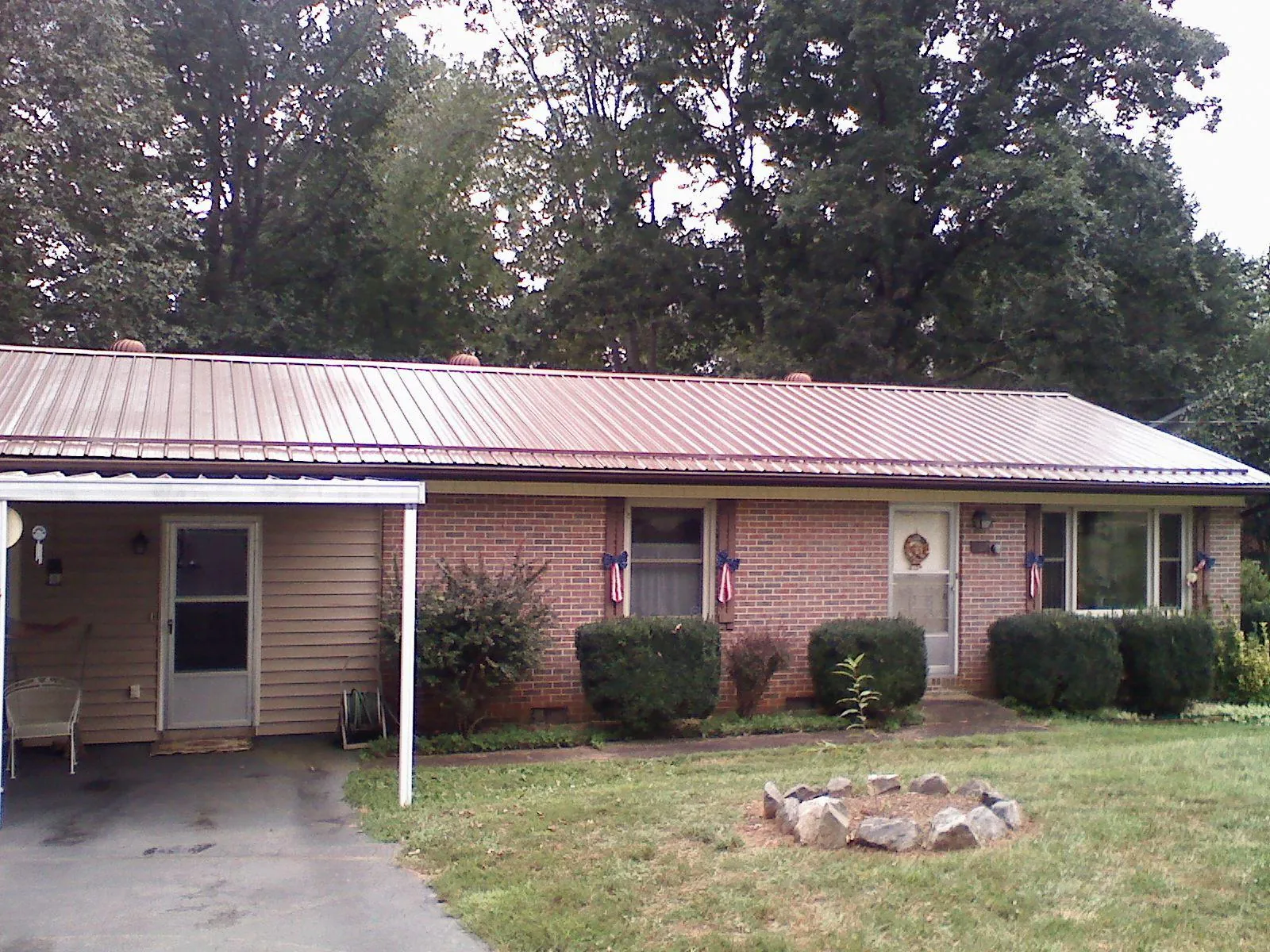 Bronze metal roof and carport on a brick ranch home — Roof Repair work by our crew in Ransomville