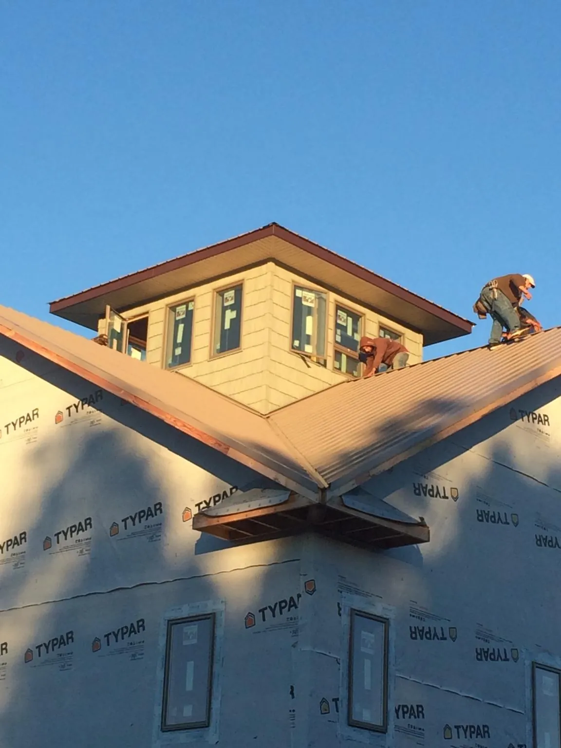 Roofers working around a rooftop cupola on a new metal roof at sunset — Roof Waterproofing in Ransomville by Roofing Brothers